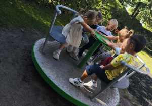 Dzieci bawią się na karuzeli w ogrodzie przedszkolnym.