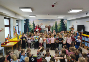 Dzieci starsze wraz z przedstawicielkami Teatru Sowa na tle tematycznej scenografii.