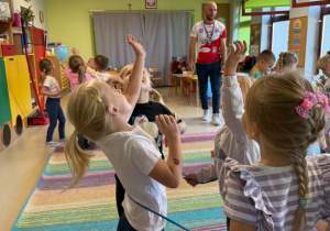 Dzieci biorą udział w zabawach ruchowych proponowanych przez trenera.