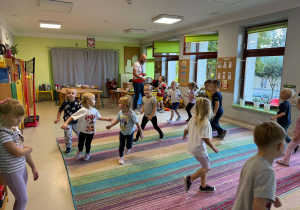Dzieci biorą udział w zabawach ruchowych proponowanych przez trenera.