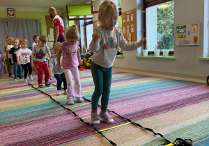 Dzieci biorą udział w zabawach ruchowych proponowanych przez trenera.