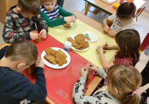Kilkoro dzieci przy stole zaczyna zdobić wcześniej przygotowane pierniczki.