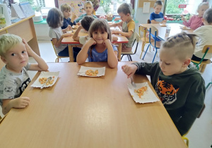Dzieci jedzą przygotowaną wspólnie sałatkę.